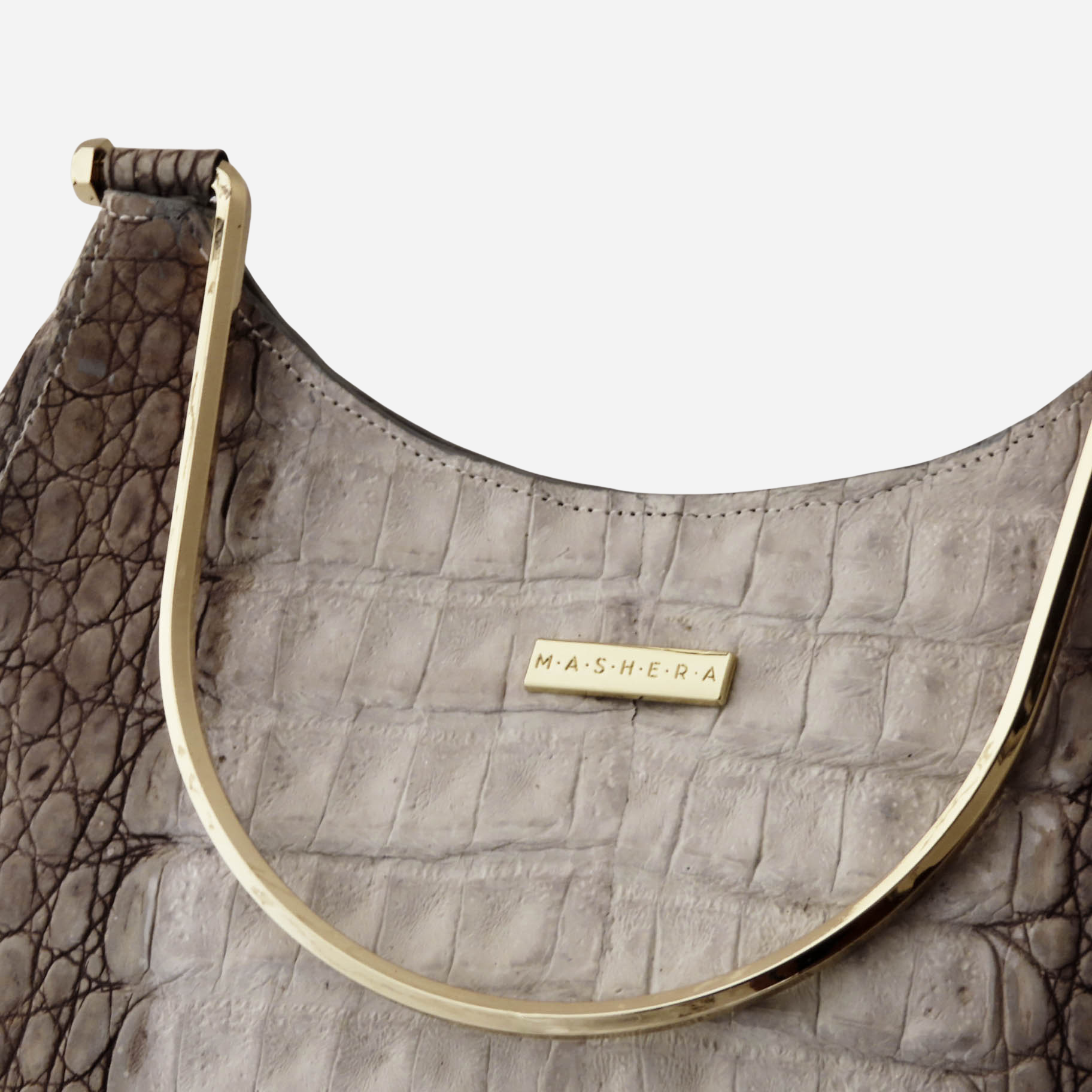 Detalles del bolso Quimbaya bicolor. Primer plano de textura piel de cocodrilo y asa dorada.