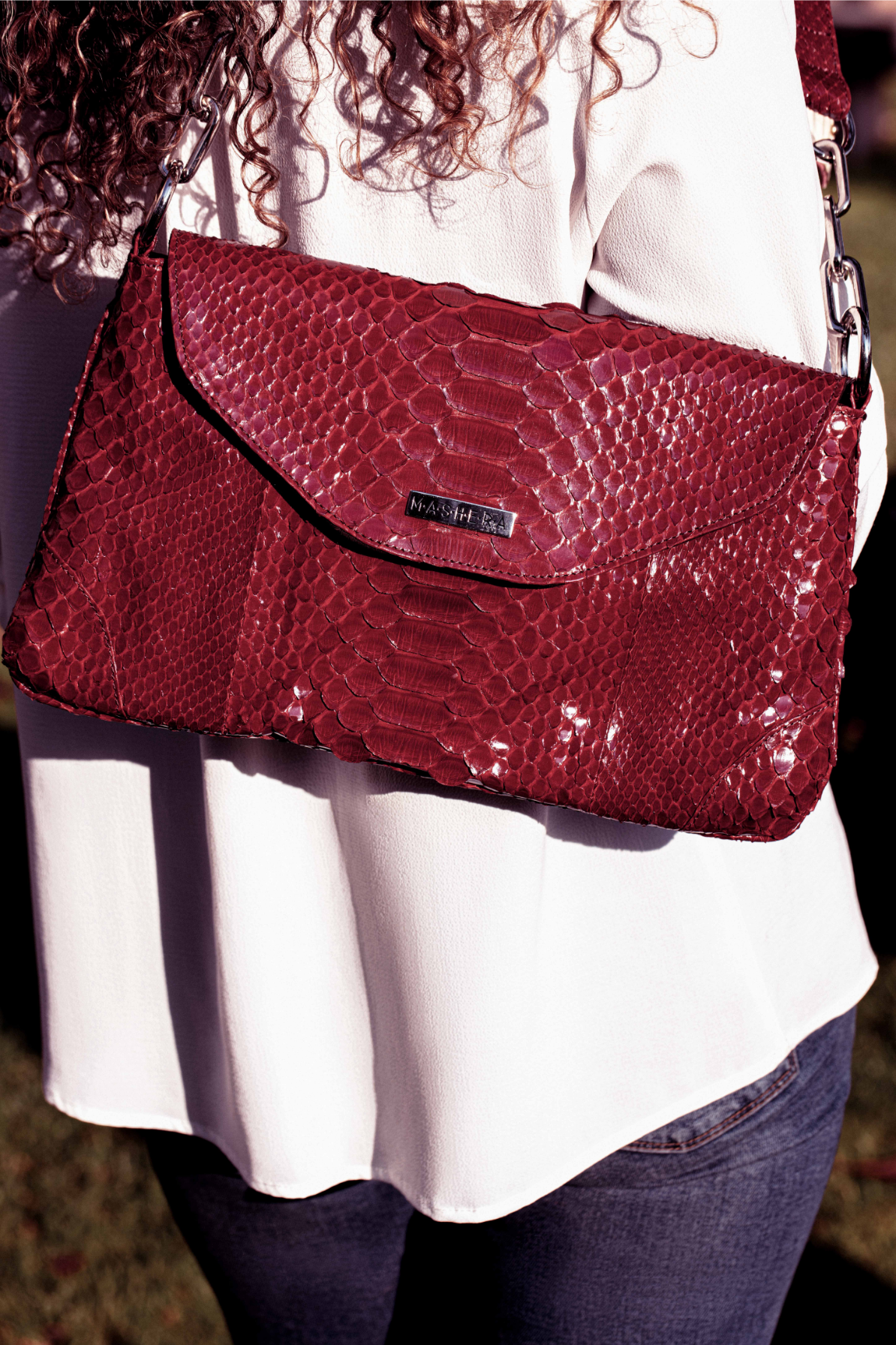 Modelo portando el Bolso CLEMENTINA rojo en pitón genuino con tapa imantada en forma de diamante .