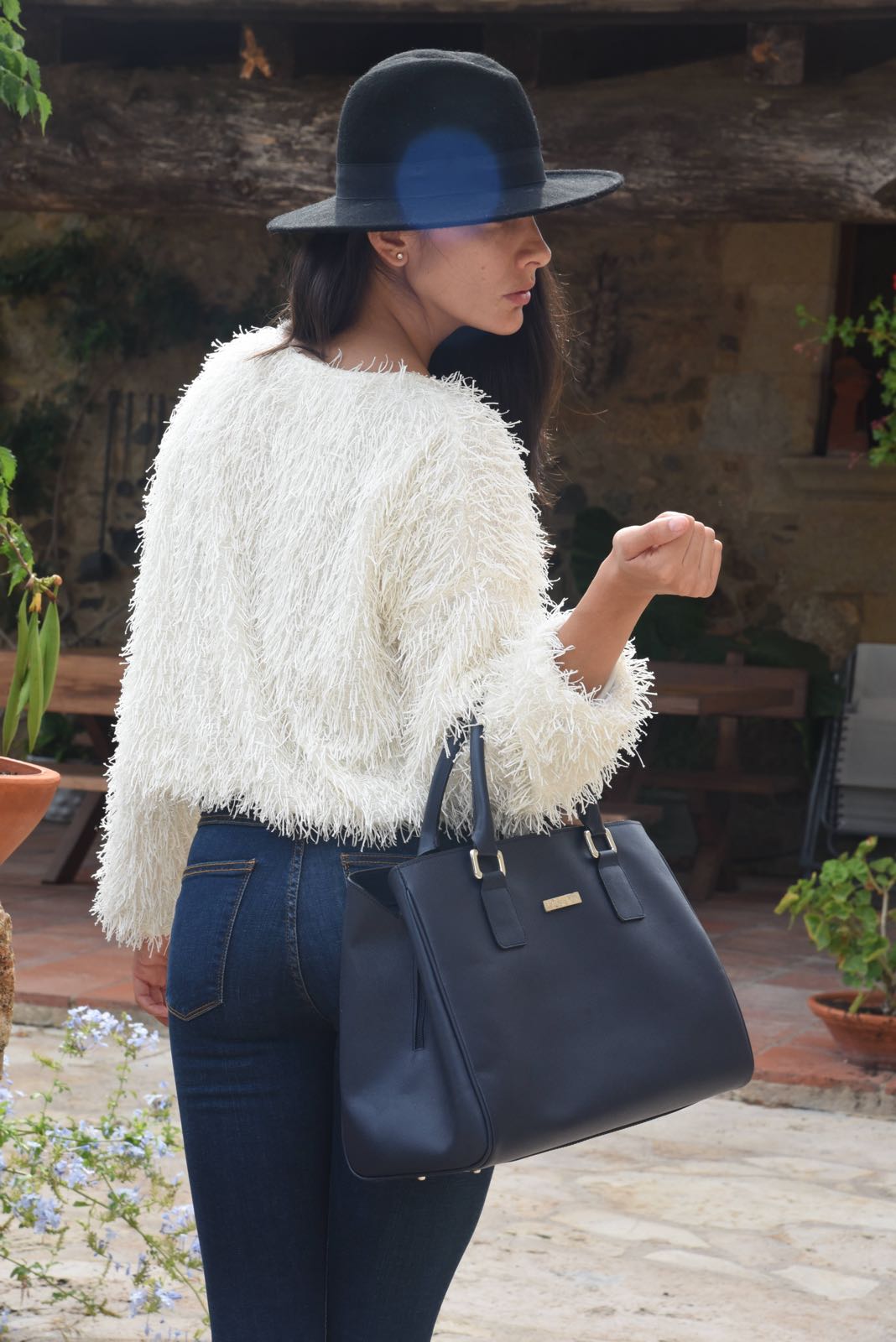 Modelo luciendo  en el exterior de una casa de campo el Bolso ERMITA azul oscuro en piel con asas - accesorio funcional discreto artesanal.