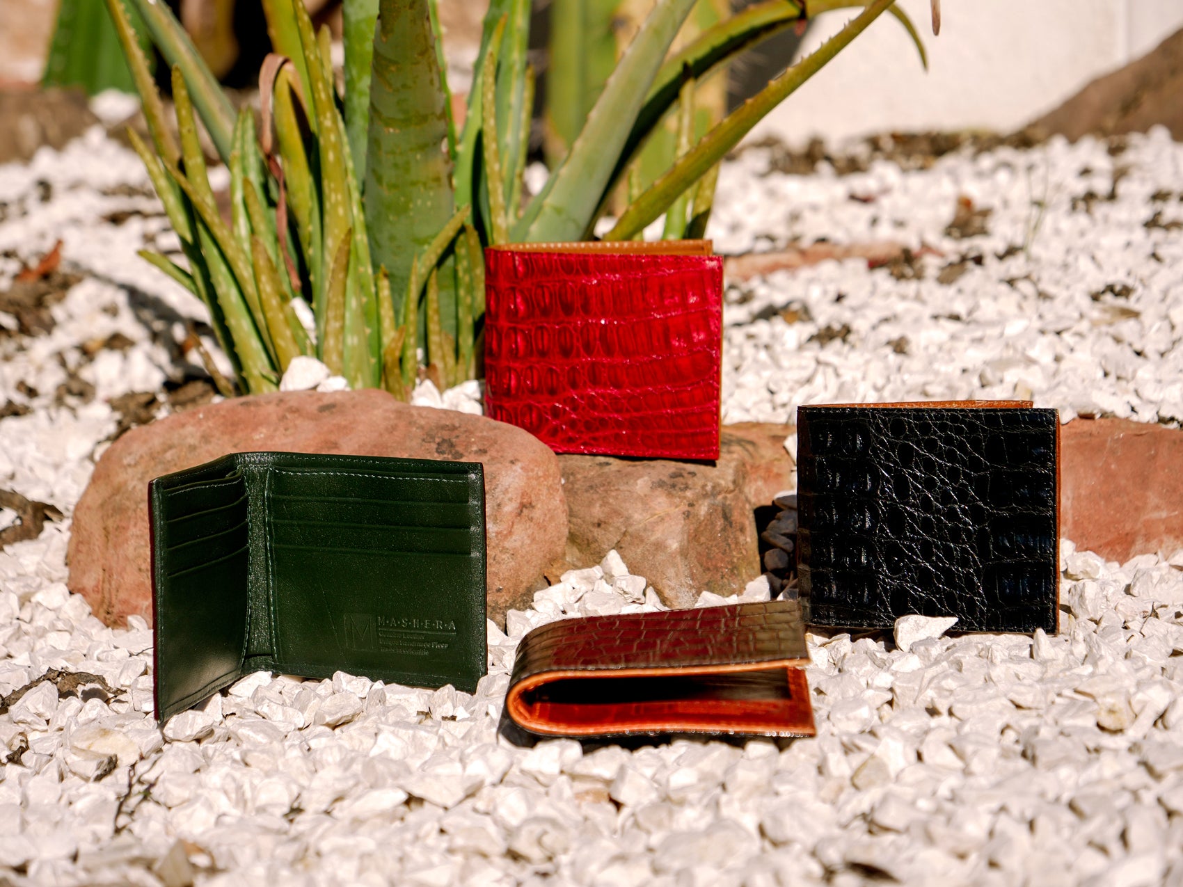 Presentación en un entorno natural y variedad de Carteras NADÚ en verde, rojo, negro y marrón en piel grabada - diseño funcional elegante artesanal
