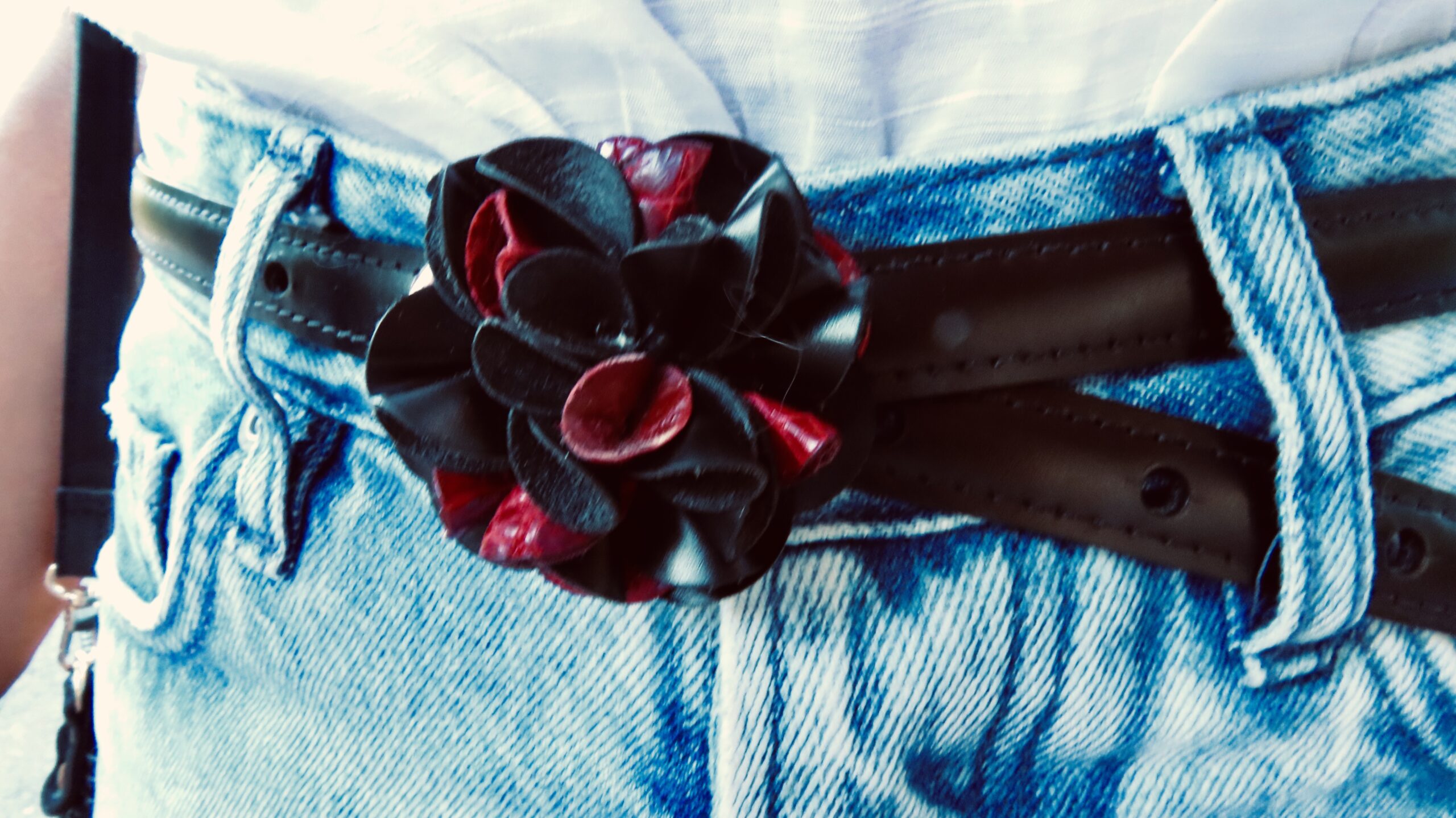 Modelo llevando sobre unos jeans el  cinturón FLORA con hebilla de flores artesanales en tonos rojo y negro.